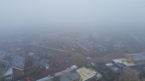 aerial of a beautiful suburban neighborhood covered in thick mist on a cold winter day - drone flying backwards