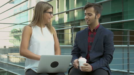 Multiethnic-business-people-using-laptop-and-shaking-hands