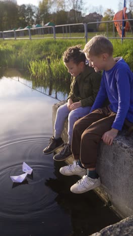 kinder sitzen in der nähe des teiches