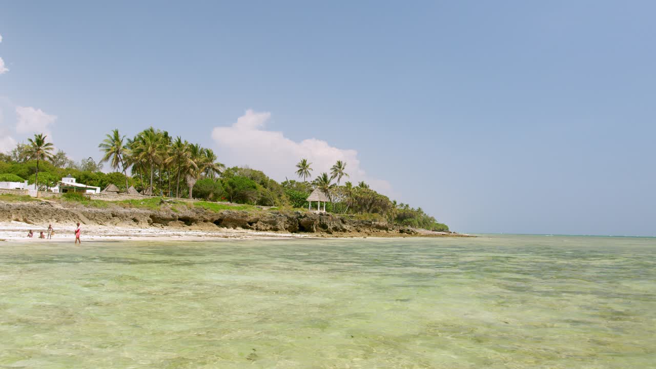 Vesničané na tropickém pobřeží u Indického oceánu v Diani Beach, Keňa, Afrika.