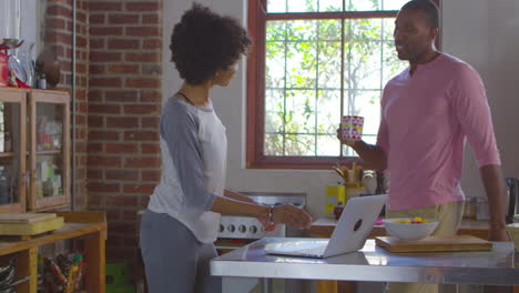 Mixed-race-couple-using-laptop-computer-talking-in-kitchen,-shot-on-R3D