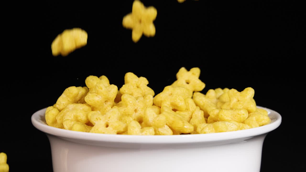 Star-shaped cereal pieces drop into a white bowl against a black background, creating a dynamic and playful visual effect