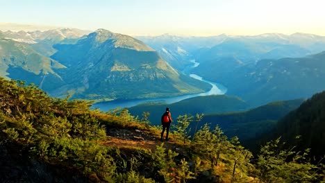 hiker on a mountain ridge overlooking a valley at sunrise