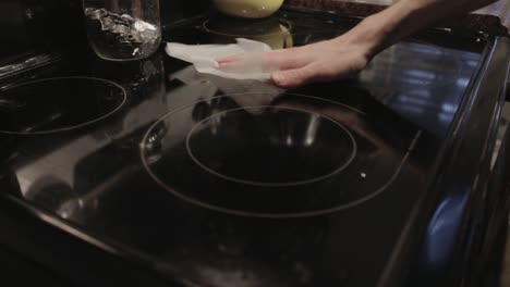 wiping the clear glass gas stove with wet wipes - close up shot