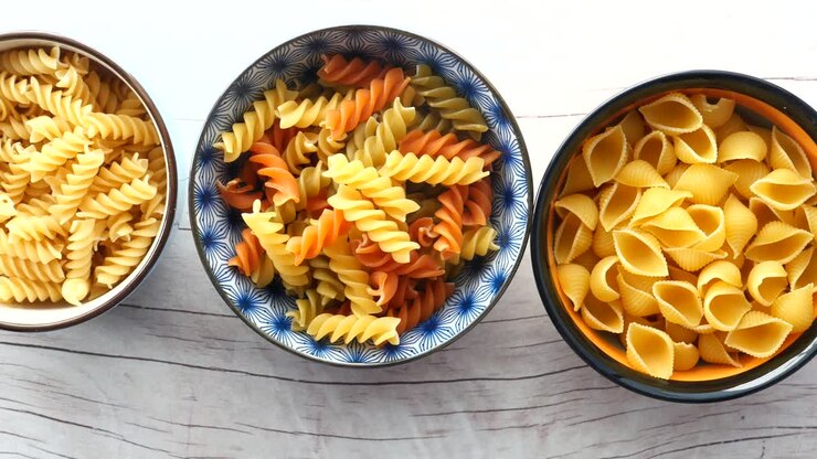 Diversi tipi di pasta in ciotole su un tavolo di legno