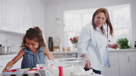 Aufgeregtes-Junges-Mädchen-Und-Ihre-Großmutter-Backen-High-Five-Und-Legen-Kuchen-Zum-Backen-In-Den-Ofen,-Nahaufnahme