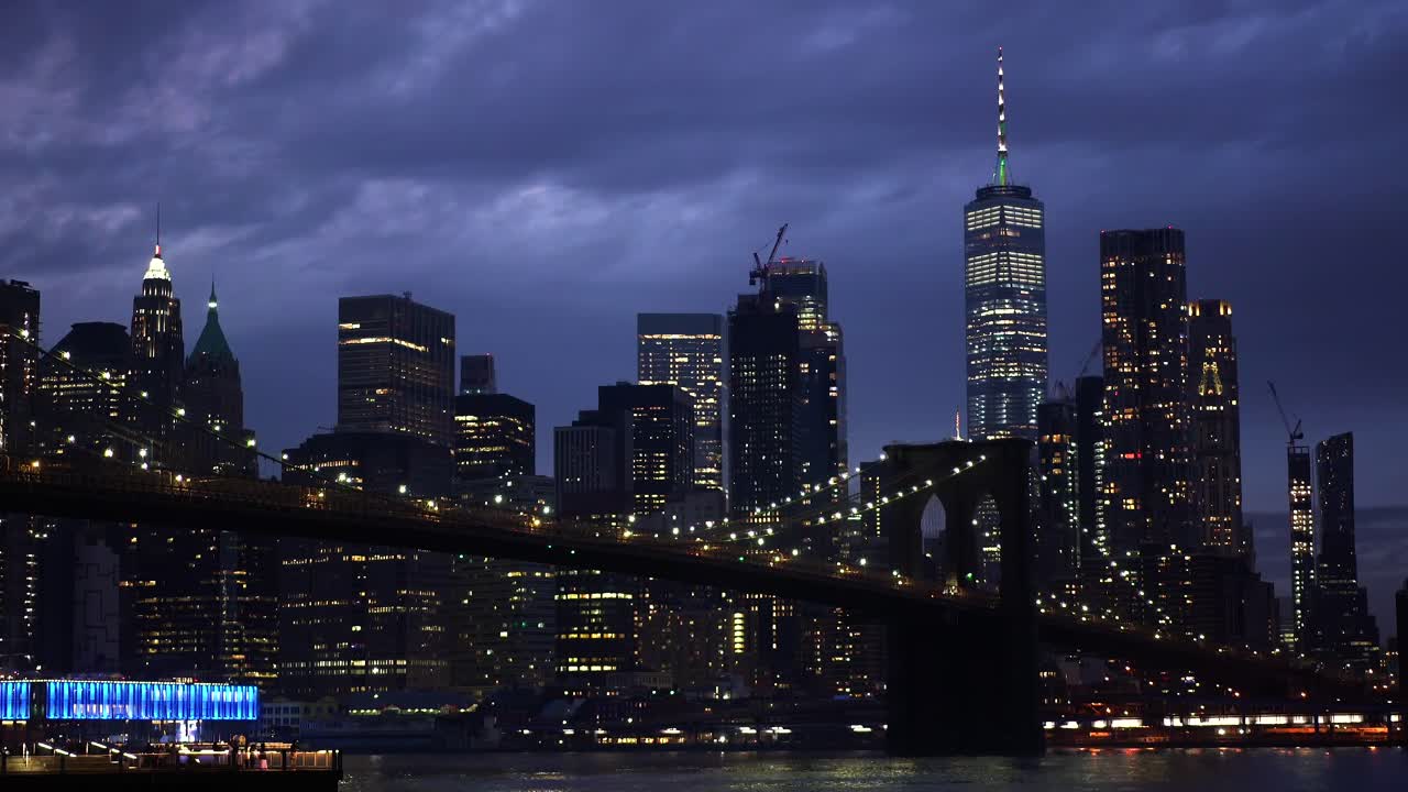 Timelapse di nuvole scure che si muovono sopra il Ponte di Brooklyn illuminato e lo skyline di Manhattan, negli Stati Uniti, in un'atmosfera cupa