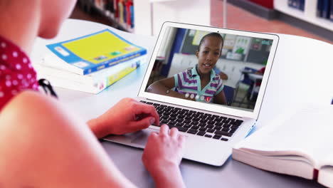 sección media de una maestra caucásica haciendo una videollamada con una colegiala en una computadora portátil en la escuela
