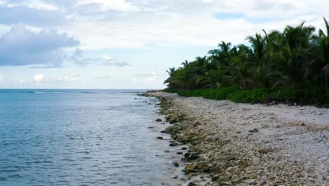 Wunderschöner-Luftwagen-In-Drohnenaufnahme-Der-Tropischen-Küste-Von-Playa-Del-Carmen-Mit-Kleinen-Wellen,-Die-An-Einem-Warmen,-Sonnigen-Sommertag-Auf-Die-Felsen,-Weißen-Sand-Und-Palmen-An-Der-Riviera-Maya,-Mexiko,-Treffen