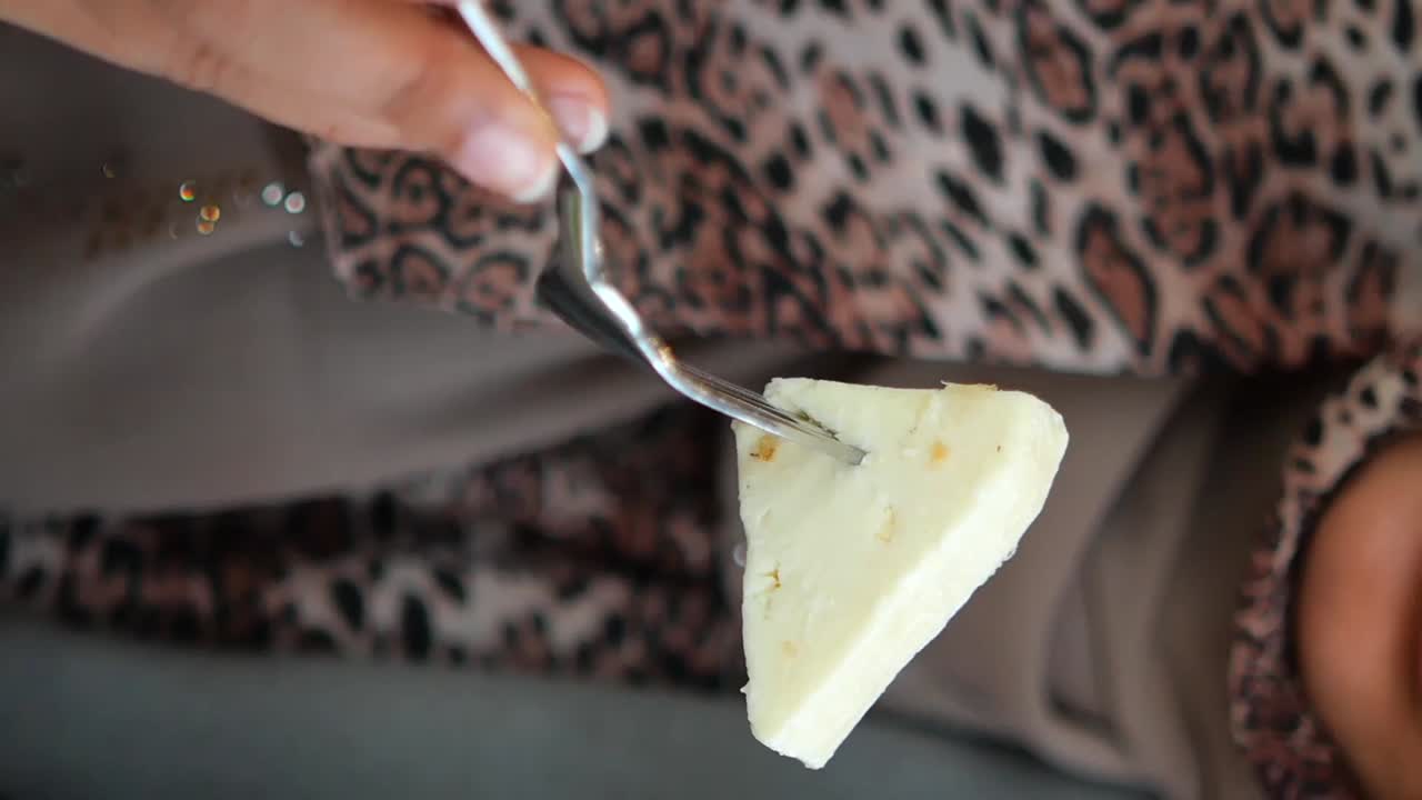 Primer plano de una mano pinchando un trozo de queso con un tenedor