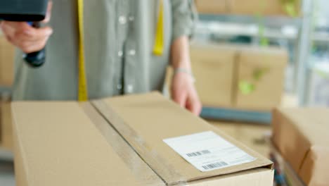 vista cercana de las manos de la mujer escaneando la etiqueta en una caja en la oficina de correos o en el servicio de entrega