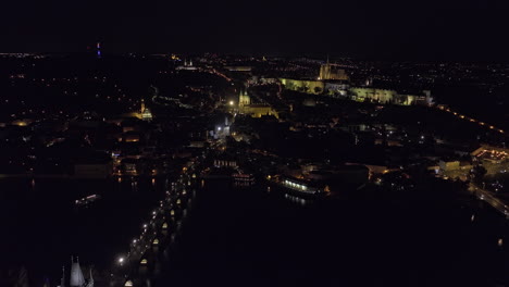 프라하 (prague) 체코 (czechia) 에어리얼 v89 드론 플라이오버: 타바 강을 따라 찰스 다리를 따라 말라 슈트라나 (mala strana) 로 향하며, 하드카니 (hradcany) 의 언덕 꼭대기에 있는 성과 야간 도시 풍경을 포착합니다.