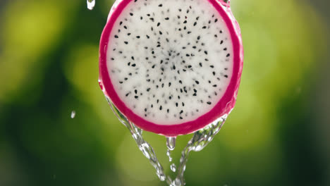 water flowing down fresh dragon fruit slice in slow motion with bright backlit background