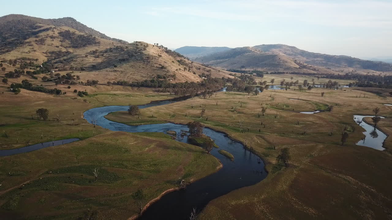aerial de un río en el interior de australia, el cielo reflejando, rodeado de montañas épicas al anochecer