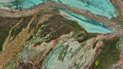 vista azimutal aérea de un avión no tripulado a baja altitud, centrándose en el fondo del valle de grænihryggur y la roca verde en landmannalaugar, islandia, destacando tonos medios de naranja y verde