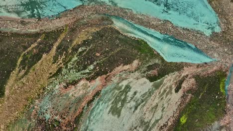 aerial drone azimuthal view at low altitude, focusing on the bottom of grænihryggur valley and the green rock in landmannalaugar, iceland, highlighting medium tones of orange and green