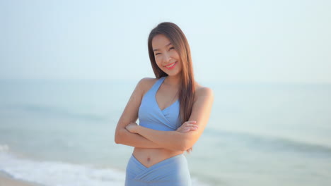 바다를 배경으로 활동복 미소를 짓고 있는 자신감 있고 만족스러운 젊고 건강한 여성