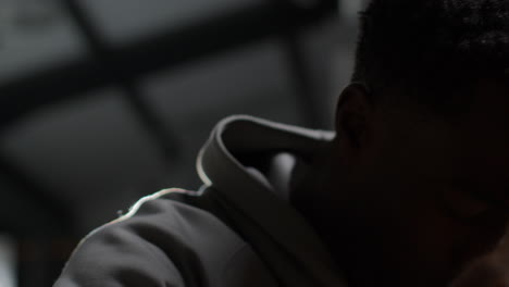 close up low key lighting shot of unhappy angry or depressed young man with head in hands shaking head