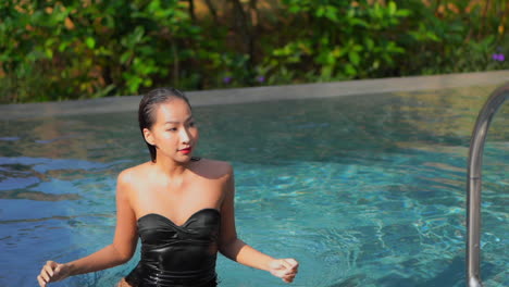 close-up-follow-shot,-of-a-very-attractive-woman-exiting-a-resort-swimming-pool-by-way-of-the-ladder