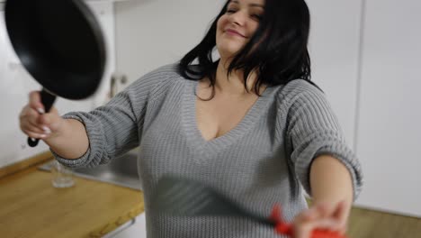 Attractive-plus-size-young-woman-dancing-energetic-while-cooking-on-kitchen
