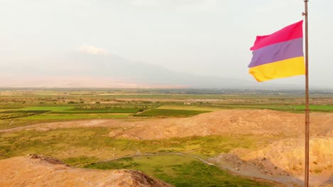 vista aérea cercana bandera armenia en un día de viento al aire libre con el campo y el fondo de las montañas de ararat