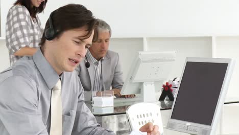 Elegant-businessman-with-headset-on-and-his-team