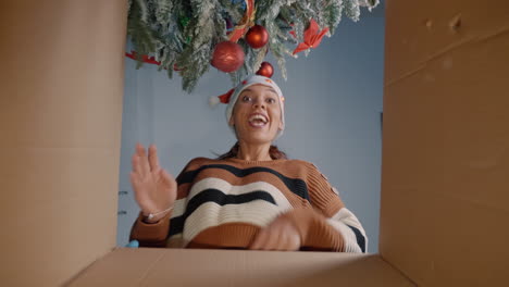 young woman opening christmas present under tree