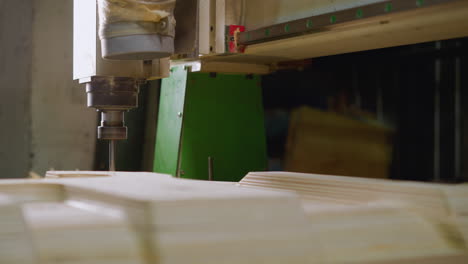 router cnc en acción en madera contrachapada en capas, entorno de taller con fondo de máquina verde