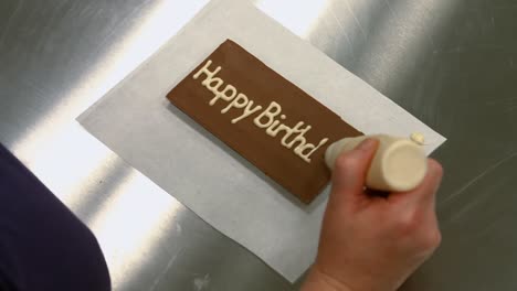 worker writing happy birthday on a chocolate plaque