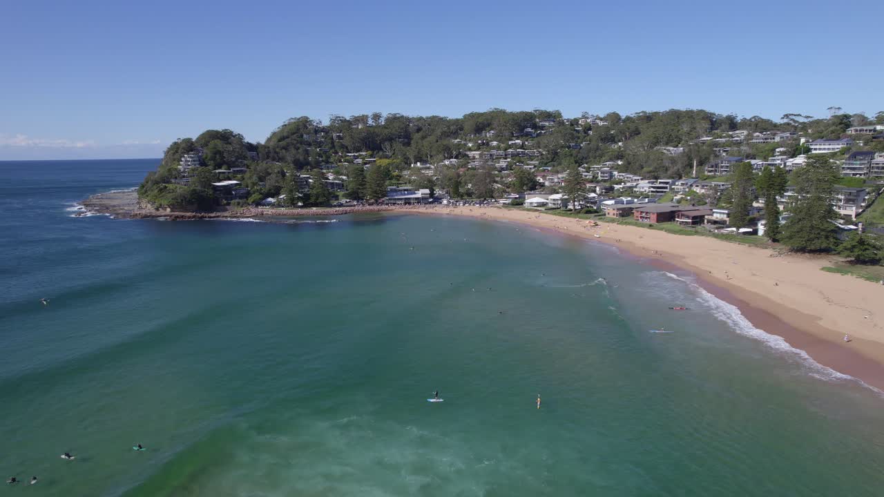 Turister svømmer og surfer om sommeren på Avoca Beach i New South Wales.