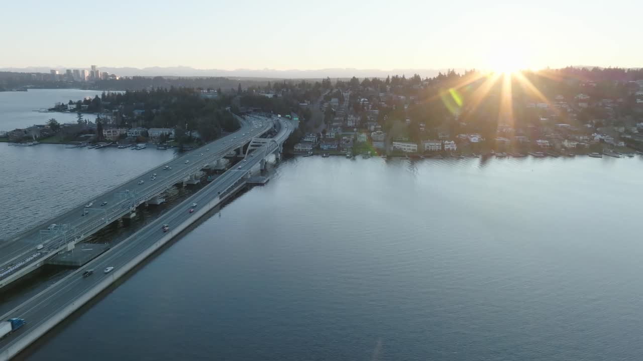 Breathtaking drone flight over Seattle's islands at sunset, showcasing the iconic floating bridge and cars heading towards the coastal area.