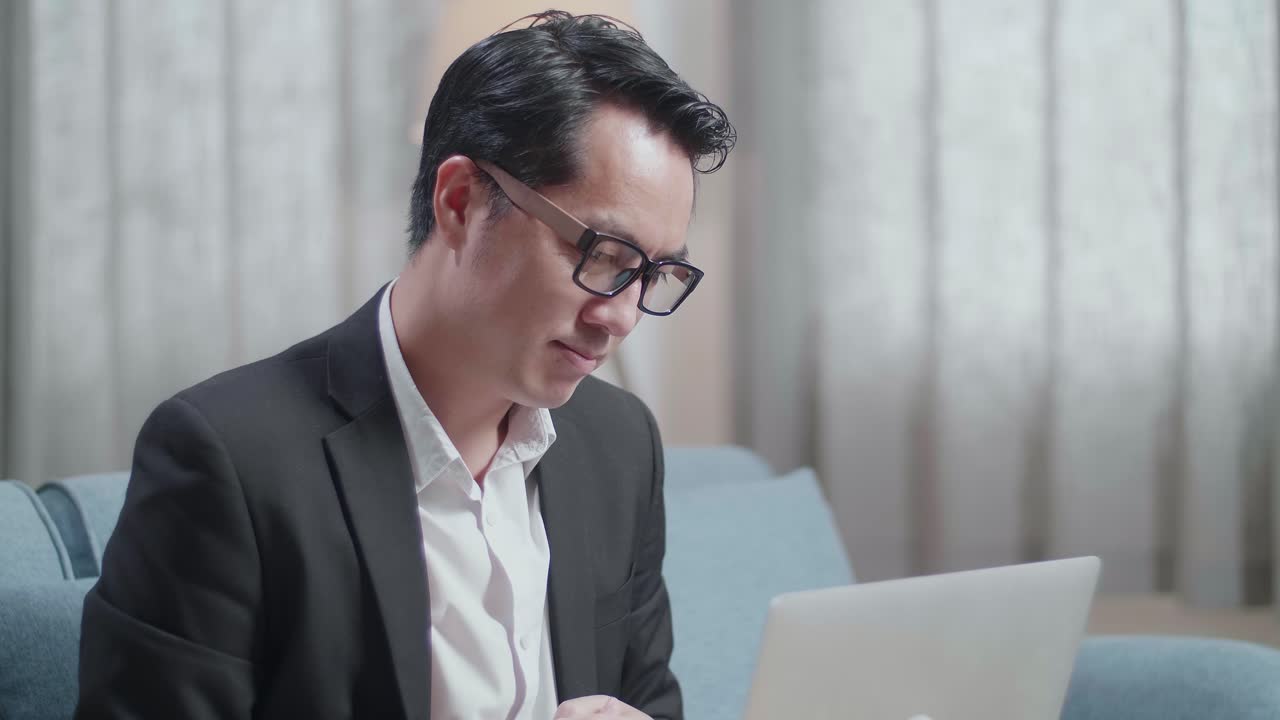 집에서 노트북으로 비디오 통화를 하는 동안 엄지손가락을 올리는 제스처를 보여주는 재과 쇼트를 입은 아시아 사업가의 클로즈업