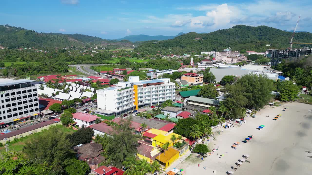 impresionante vista aérea de una bulliciosa playa tropical bordeada de edificios turísticos, pintorescas colinas y tranquilas aguas turquesas en malasia
