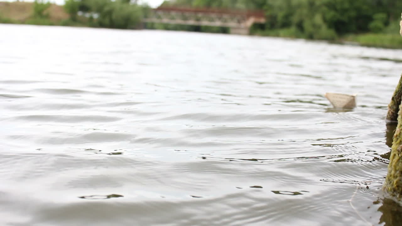 The Boy Playing Near Water. The boy playing launches a paper boat