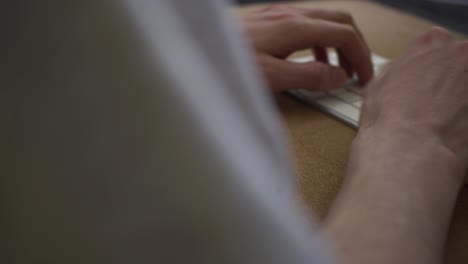 Moving-shot-of-a-guy-typing-on-his-computer-at-his-desk