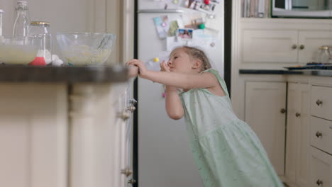 happy little girl taking cookie sneaky child stealing biscuit in kitchen at home