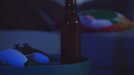game night with console controller and bottle of beer inside cozy room, handheld shot