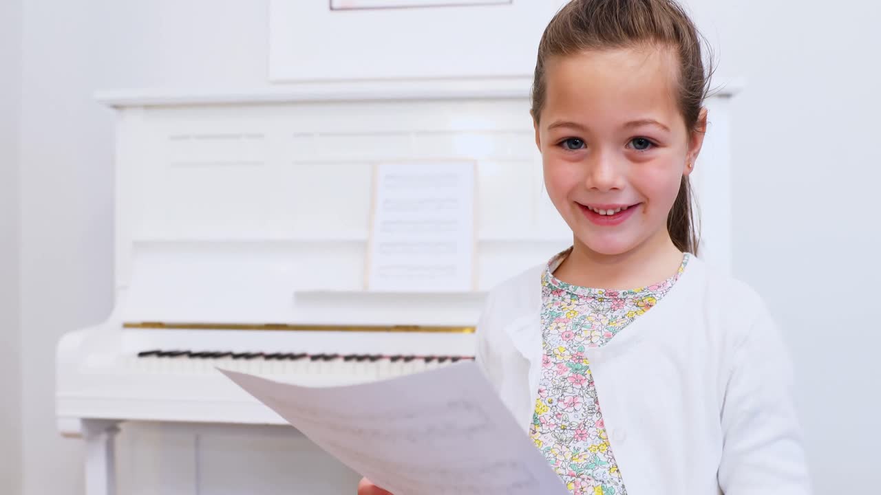 Cute girl holding sheet music at home 4k