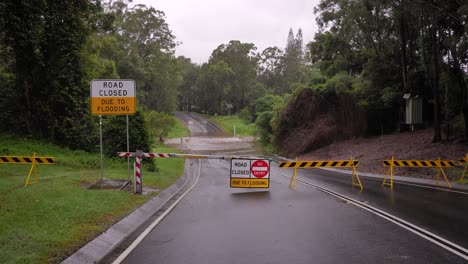 gold coast, queensland, 16 february 2024 - wide shot of road closure signage and flooding across hardy's road in mudgeeraba after heavy rains continue to lash south east queensland, australia