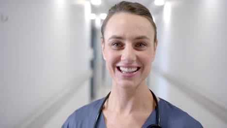 Portrait-of-happy-caucasian-female-doctor-in-hospital-corridor,-slow-motion