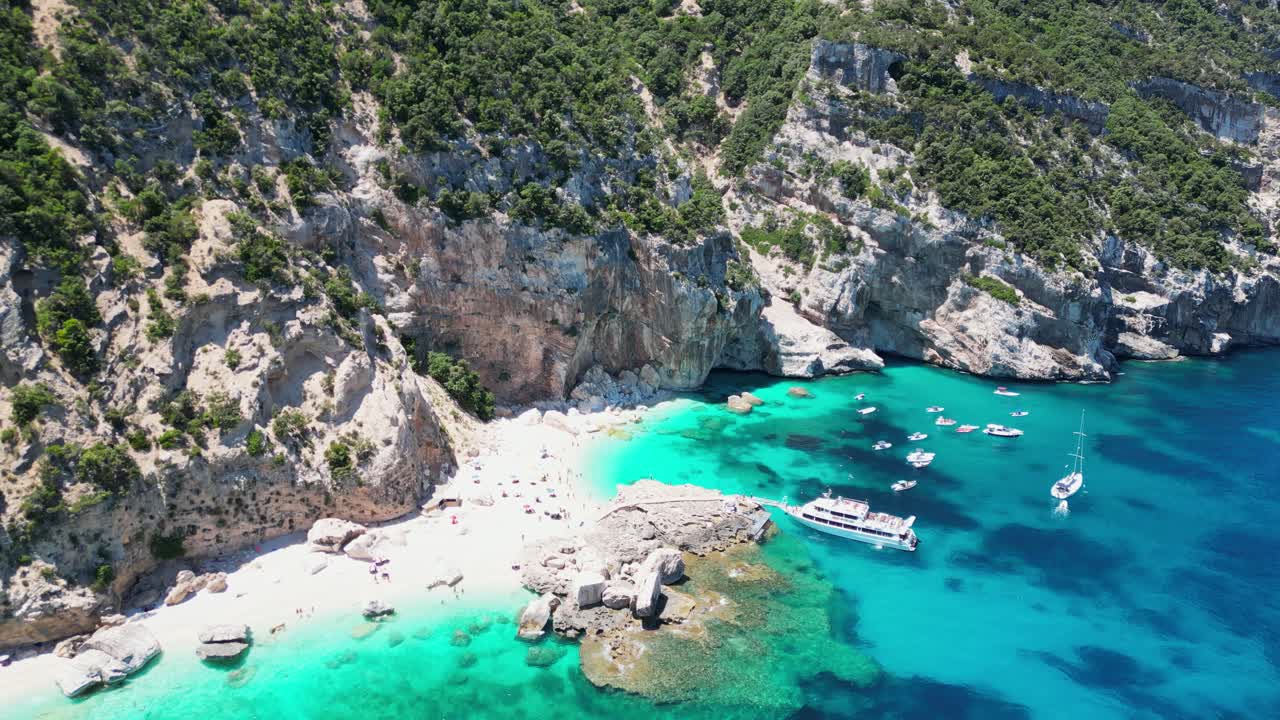 Bådtur-udflugt henter turister ved Cala Mariolu Strand, Baunei-kysten, Sardinien, Italien - Cirkulerende luftfoto 4k