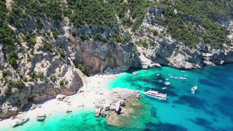 Excursión-En-Barco-Para-Recoger-Turistas-En-La-Playa-De-Cala-Mariolu,-Costa-De-Baunei,-Cerdeña,-Italia---Círculos-Aéreos-De-4k