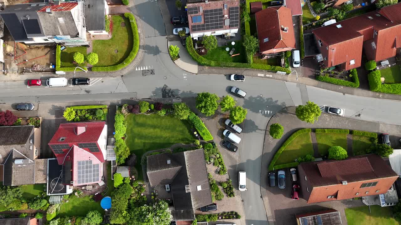 Pittoresco quartiere residenziale americano, che mostra case ben curate, prati verdi e strade ordinate. Ripresa aerea in tracking di un'auto che guida per le strade della città in estate. Pannelli solari sul tetto