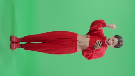 Full Body Of Young Asian Transgender Male Celebrating With Mobile Phone While Standing On Green Screen In The Studio