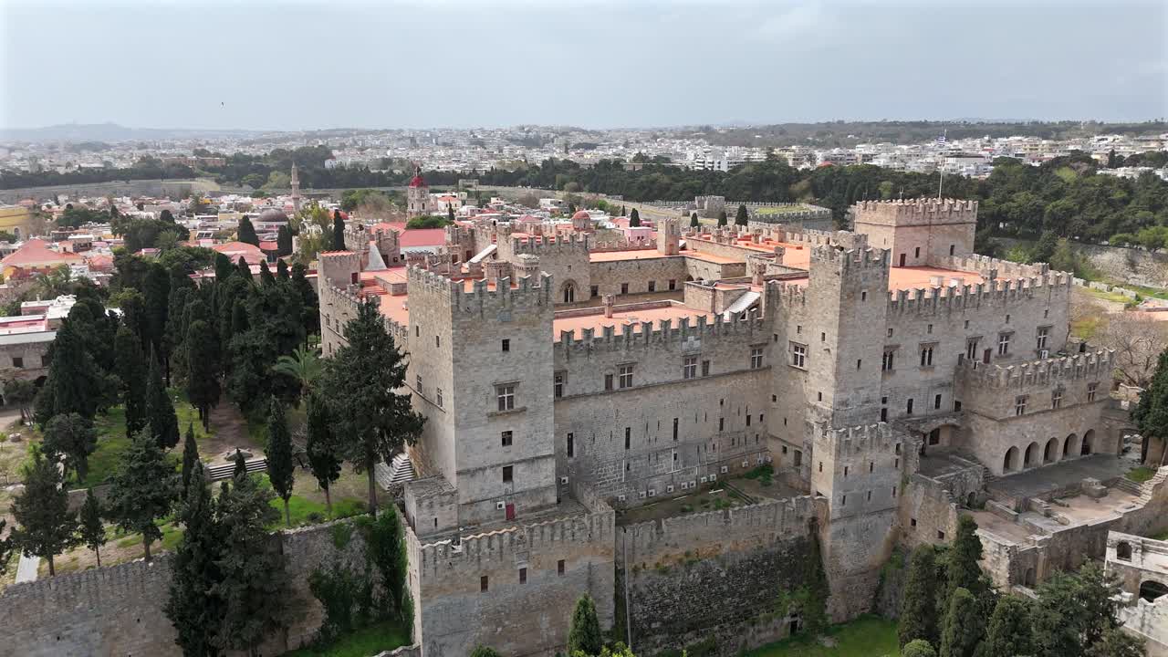 Aerial backwards from The Grand Master's Palace of the Knights at Rhodes Island on a sunny day. Castle walls surrounded by the trees.