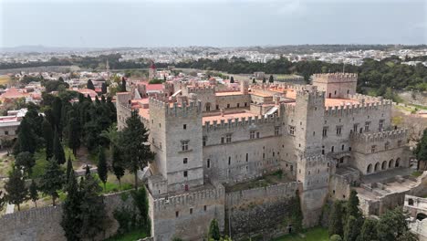 aerial backwards from the grand master's palace of the knights at rhodes island on a sunny day. castle walls surrounded by the trees.