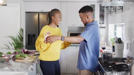 Happy-african-american-couple-dancing-in-kitchen