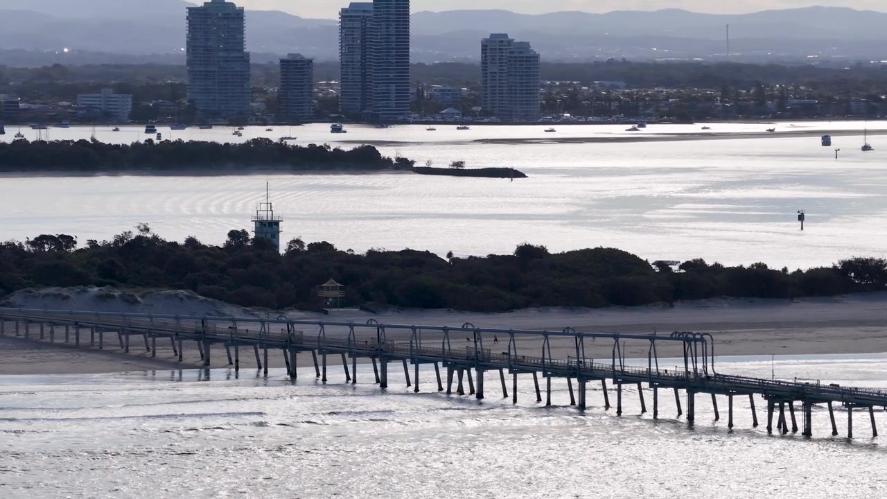 Weite Luftaufnahme der industriellen Sandbypass-Mole und der Skyline von Surfers Paradise in Australien