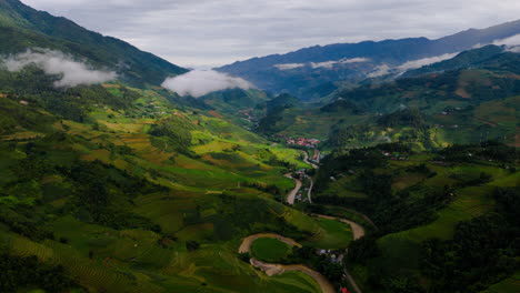 aerial view of lush green rice terraces and village in a mountainous valley