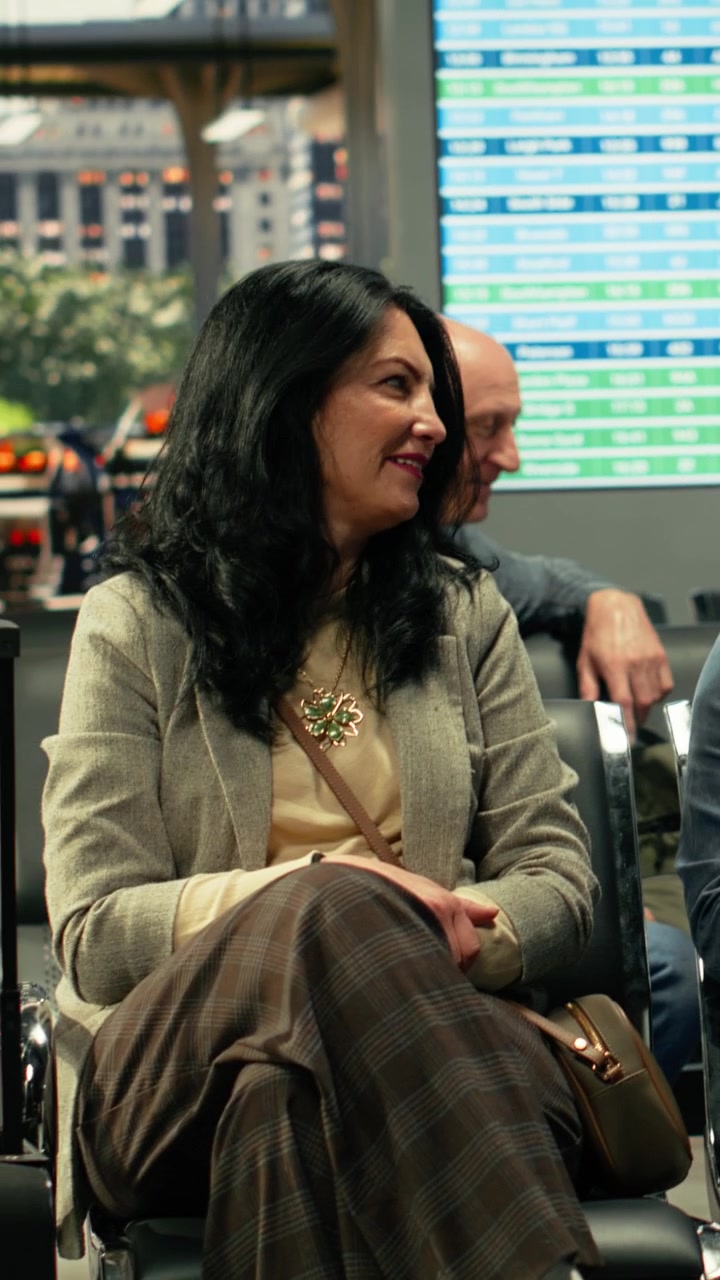Diverse travelers seated in busy coach station with luggage near departure board